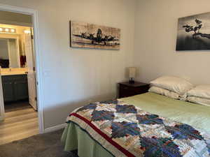 Bedroom with a sink, light colored carpet, baseboards, and connected bathroom