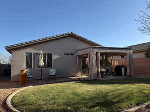 Rear view of property featuring a patio area, fence, a lawn, and stucco siding