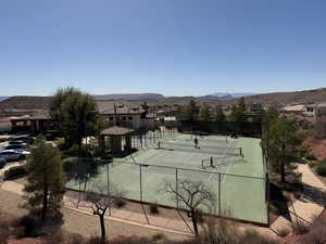 View of tennis court with a mountain view and fence