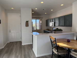 Kitchen with stainless steel appliances, visible vents, wood finished floors, and light countertops