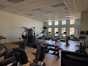 Workout area featuring visible vents, a high ceiling, baseboards, and a drop ceiling