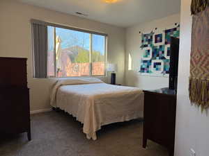 Bedroom with baseboards, visible vents, dark carpet, and a textured ceiling