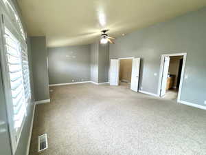 Unfurnished bedroom featuring visible vents, baseboards, ceiling fan, light colored carpet, and high vaulted ceiling