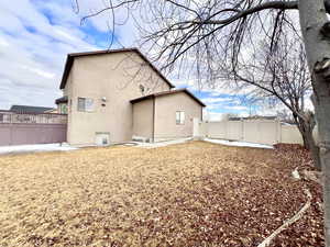 Rear view of property featuring stucco siding and fence