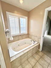 Full bath with tile patterned floors and a whirlpool tub