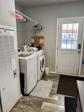 Laundry area with wood finished floors, separate washer and dryer, baseboards, a heating unit, and laundry area