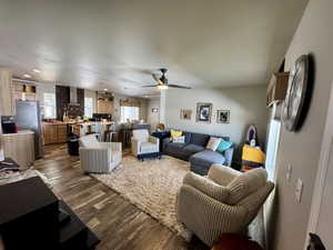 Living area featuring a ceiling fan and dark wood-style flooring
