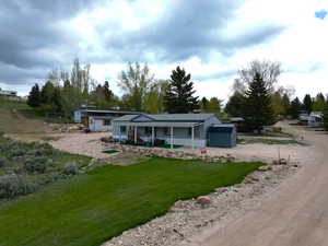 View of front facade featuring driveway, covered porch, and a front yard