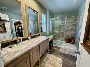 Bathroom with visible vents, a stall shower, wood finished floors, and a sink