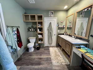 Full bath featuring wood finished floors, visible vents, double vanity, a sink, and toilet