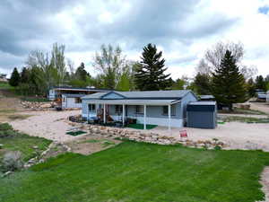 View of front of house with a porch, a front yard, roof with shingles, and an outdoor structure