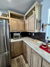 Kitchen with backsplash, dark wood-style floors, freestanding refrigerator, a toaster, and light countertops