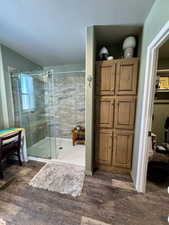 Full bath featuring wood finished floors, a stall shower, and a textured ceiling