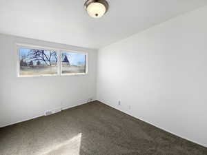 Unfurnished room with visible vents and dark carpet