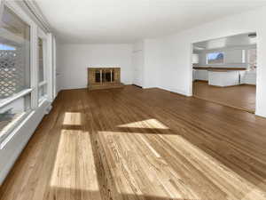 Unfurnished living room featuring a stone fireplace, wood finished floors, and visible vents