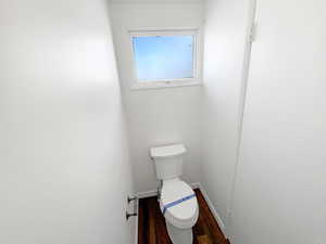 Bathroom featuring baseboards, toilet, and wood finished floors