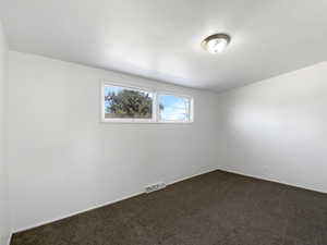 Spare room with visible vents and dark colored carpet