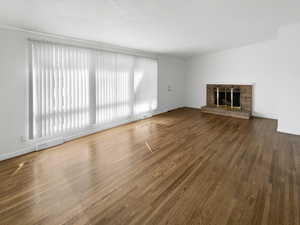 Unfurnished living room with wood finished floors, a fireplace, visible vents, and baseboards