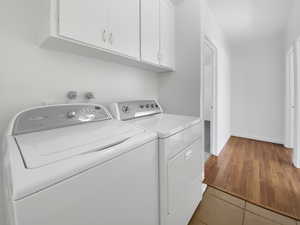 Laundry area with light tile patterned floors, cabinet space, independent washer and dryer, and baseboards