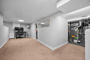 Office space with light carpet, heating unit, and baseboards