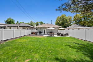 Rear view of house featuring a fenced backyard, a patio, brick siding, and a lawn