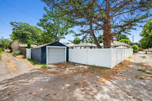 Detached garage with a gate, fence, and driveway