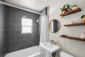 Bathroom with shower / bath combination with curtain, a sink, and toilet