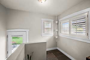 Interior space featuring dark tile patterned floors, baseboards, and a textured ceiling