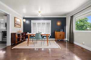 Dining room featuring wood-type flooring, visible vents, and ornamental molding