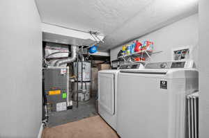 Laundry room featuring gas water heater, washer and clothes dryer, a textured ceiling, and laundry area