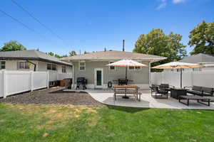 Back of property featuring a lawn, a fenced backyard, a patio area, an outdoor living space, and brick siding