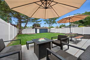 View of patio with a storage shed, an outdoor fire pit, a fenced backyard, an outdoor structure, and outdoor dining space