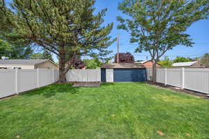 View of yard with a fenced backyard, a shed, and an outbuilding