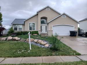 View of front of property with stucco siding, concrete driveway, a garage, and a front lawn