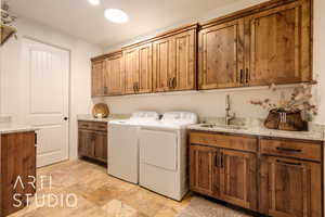 Laundry area featuring washing machine and clothes dryer, cabinet space, and a sink