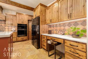 Kitchen featuring light countertops, stone finish floor, double oven, backsplash, and black fridge