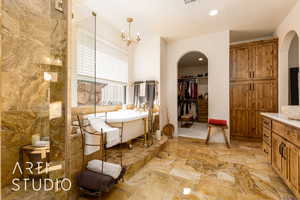 Primary Bathroom with a notable chandelier, recessed lighting, and a freestanding bath