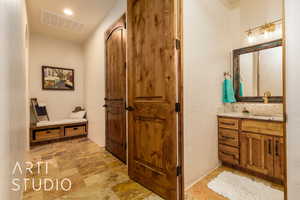 1/2 Bathroom featuring vanity, and stone finish flooring