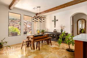 Dining space with beamed ceiling, arched walkways, and textured ceiling.