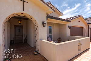 Entrance to property featuring a tile roof, an attached garage, and courtyard patio