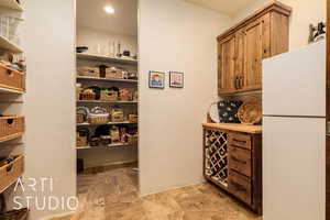 View of storage area featuring shelves, refrigerator, and wine rack