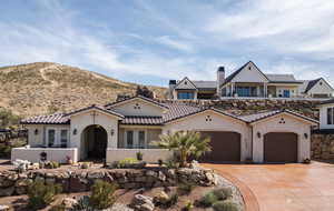 View of front of house with an attached garage, stucco siding, concrete driveway, french doors, and a tiled roof