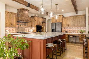 Kitchen featuring stone tile floors, beam ceiling, arched walkways, appliances with stainless steel finishes, and a kitchen bar