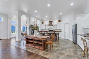 Dining area with crown molding, arched walkways, baseboards, and recessed lighting