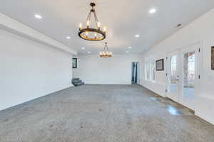 Unfurnished room featuring baseboards, carpet, recessed lighting, french doors, and a notable chandelier