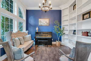 Sitting room with built in shelves, ornamental molding, hardwood / wood-style floors, and a chandelier