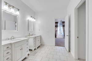 Bathroom featuring a sink, baseboards, two vanities, and tile patterned floors