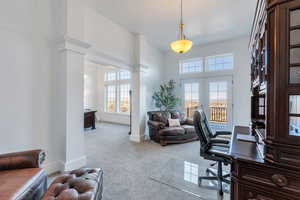 Carpeted office space featuring a towering ceiling, french doors, baseboards, and decorative columns in Primary suite
