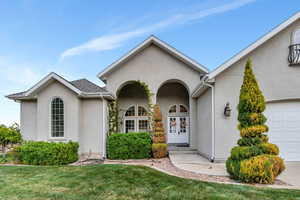 View of front of home featuring a garage, french doors, a front lawn, and stucco siding