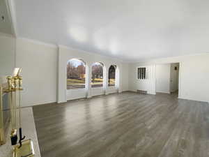 Unfurnished living room featuring visible vents, baseboards, wood finished floors, and crown molding